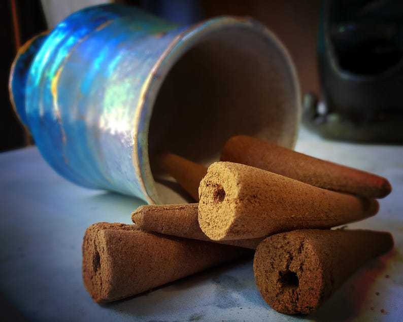 Pode incluir: Um close-up de um monte de cones de incenso marrons. Os cones est&atilde;o dispostos em uma pilha, com as pontas dos cones apontando para cima. Os cones s&atilde;o feitos de um material marrom escuro e t&ecirc;m uma textura ligeiramente &aacute;spera.
