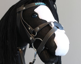 May include: Black and white stuffed horse head with a black leather bridle and a blue rhinestone browband. The horse has a black mane and tail.
