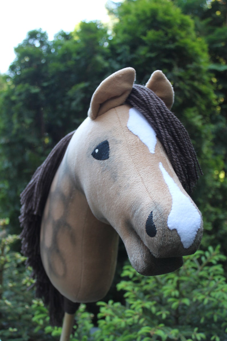 May include: A brown and white plush horse head with a brown mane. The horse has a black nose and eyes.