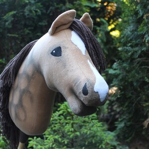 May include: A brown and white stuffed horse head with a brown mane and tail. The horse has a black eye and a white star on its forehead.