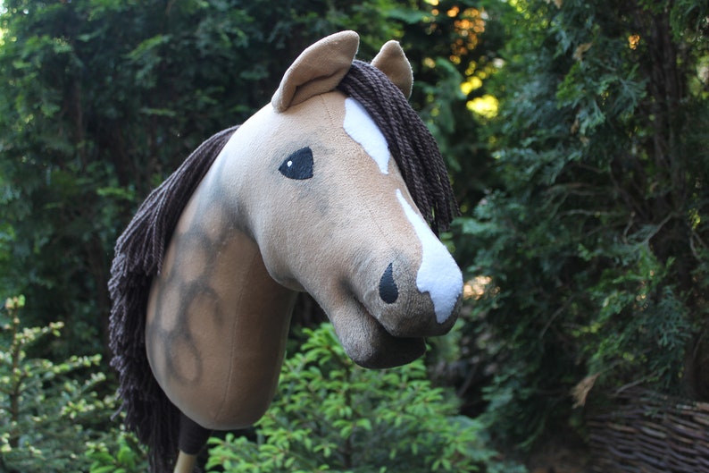 May include: A brown and white stuffed horse head with a brown mane and tail. The horse has a black eye and a white star on its forehead.