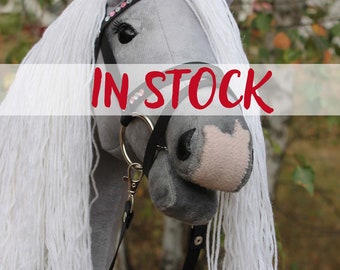 May include: A gray and white rocking horse with a black bridle and a white mane and tail. The horse is in stock.
