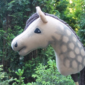 May include: A gray and white plush horse head with a brown mane and tail. The horse has a black eye and a black nose.