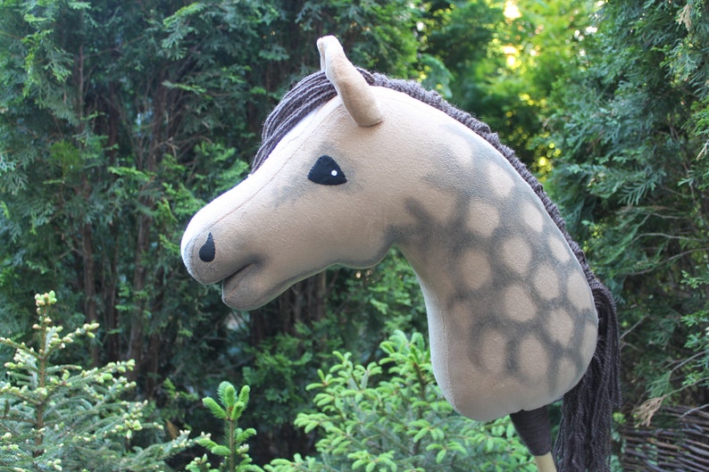 May include: A gray and white plush horse head with a brown mane and tail. The horse has a black eye and a black nose.