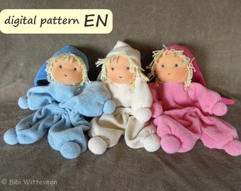 May include: Three handmade cloth dolls, each wearing a different colored outfit. The dolls are wearing blue, white, and pink pajamas. The dolls have blonde hair and painted faces. The dolls are sitting on a brown fabric surface.  The text "digital pattern EN" is in a yellow box at the top of the image.