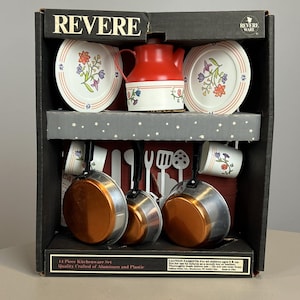 May include: A 14-piece Revere Ware kitchenware set in a black box. Includes a red and white teapot, two plates, two cups, and three pans with copper-colored bottoms and black handles. Also features white plastic utensils and printed floral designs.