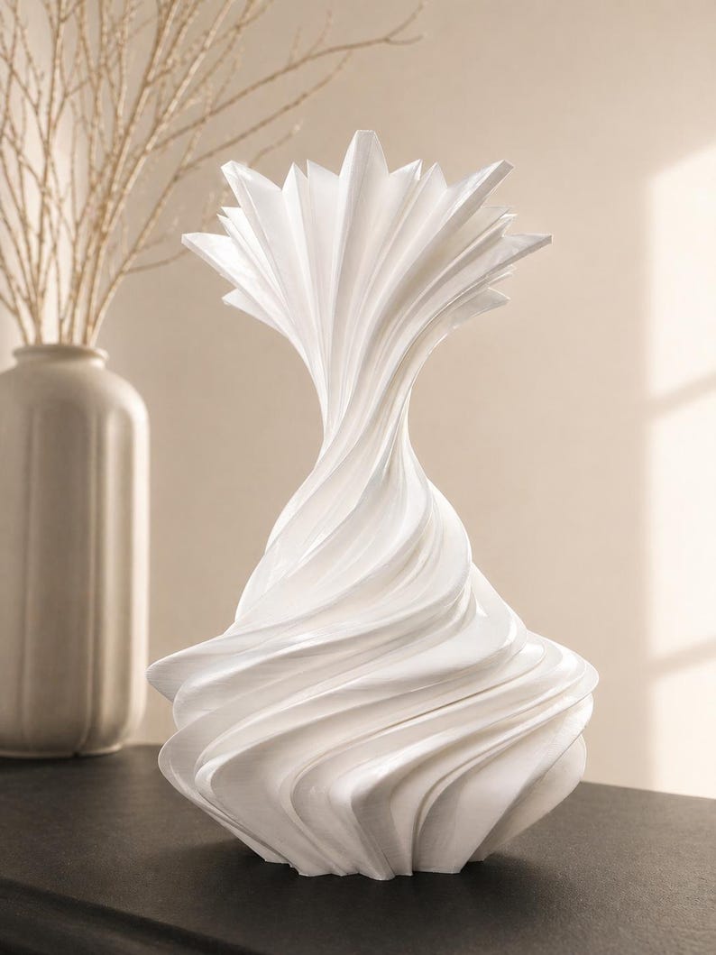 May include: A white, abstract decorative vase with a swirling, textured design. The vase has a flared base and a starburst-like top. A second, off-white vase and branches are in the background.