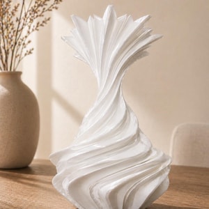 May include: A white decorative vase with a unique, swirling design. The vase has a textured, layered appearance, with a flared top and a wide, stable base. The vase is made of a solid, opaque material and is suitable for home decor.