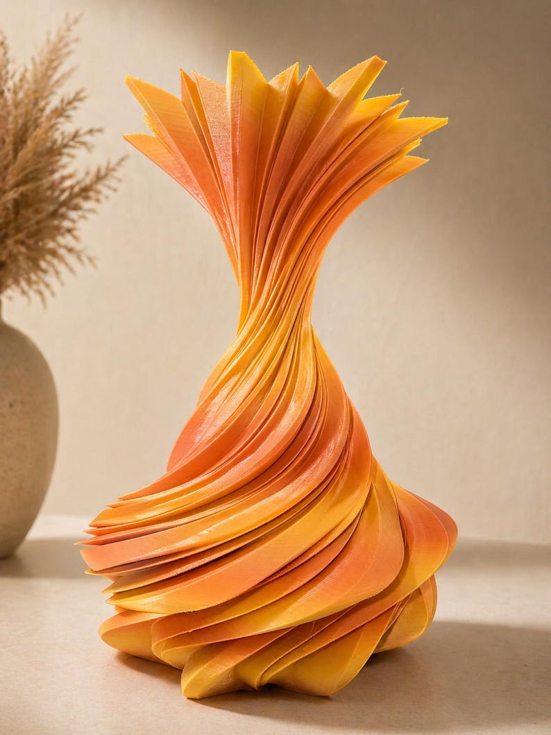 May include: A decorative vase with a unique, swirling design. The vase is made of layered, fan-shaped elements in shades of orange and yellow. The vase has a wide base that tapers to a narrow neck, and then flares out at the top.