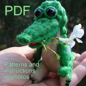 May include: Green crocheted alligator toy holding a sprig of white flowers. PDF patterns and instructions in photos.