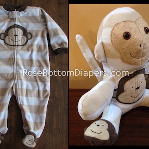 May include: A beige and white striped baby sleeper with a monkey face applique. The sleeper has a zipper closure and monkey face appliques on the feet. A stuffed monkey toy with a similar design is also shown.