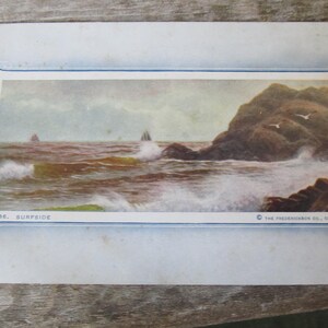 May include: A vintage postcard depicting a seascape with a rocky coastline, crashing waves, and a sailboat in the distance. The postcard is titled "Surfside" and is from The Frederick Co., Chicago.