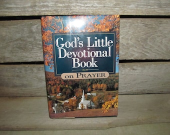 May include: A book titled "God's Little Devotional Book on Prayer" with a picture of a small town with a white church on the cover.