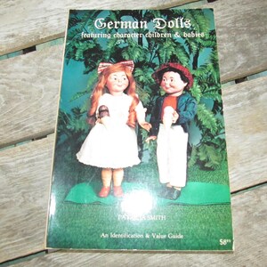 May include: A book titled "German Dolls featuring character children & babies" by Patricia Smith. The book is an identification and value guide. The cover features a color illustration of two dolls, a girl in a white dress and a boy in a blue jacket and white pants.