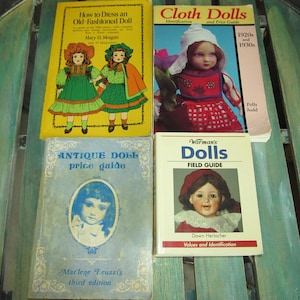 May include: Four books about antique dolls, including a price guide, a field guide, and two books on how to dress and identify cloth dolls. The books feature colorful illustrations of dolls.