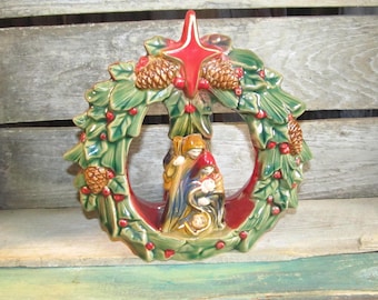 Corona navideña de la Sagrada Familia con bayas de acebo y piñas, decoración con velas de té.