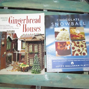 May include: Two cookbooks, one titled "Making Great Gingerbread Houses" with a gingerbread house on the cover, and the other titled "Chocolate Snowball" with a variety of pastries on the cover.