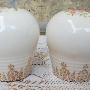 May include: Two white ceramic salt and pepper shakers with a floral design and gold trim.