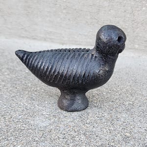 May include: A black ceramic bird sculpture with a textured surface and a round head. The bird is standing on a small base.