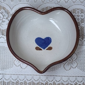 May include: A heart-shaped ceramic dish with a brown rim and a blue heart design in the center.
