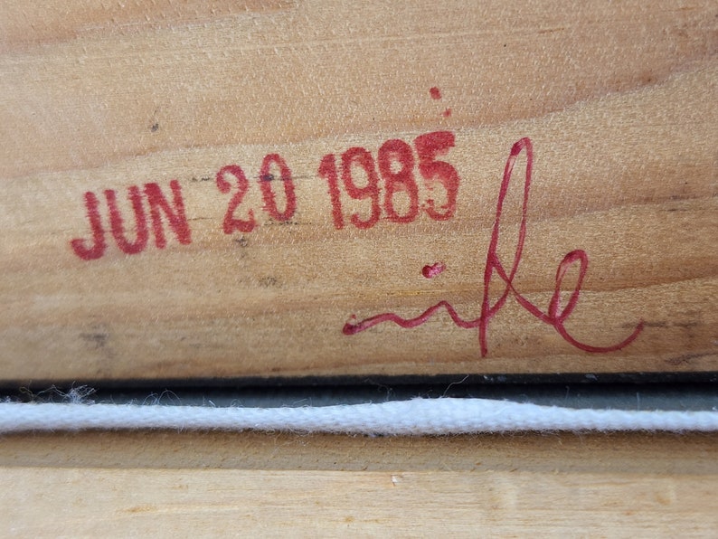 May include: Close-up of a wooden surface with a red stamp that reads "JUN 20 1985" and a red signature that reads "mike".