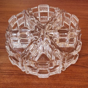 May include: A clear glass divided dish with a geometric pattern. The dish has five sections and is perfect for serving snacks or condiments.