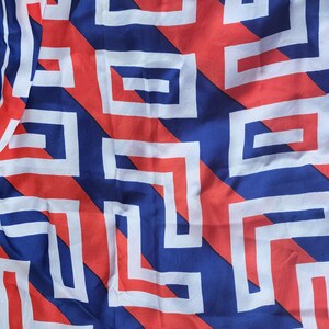 May include: A blue and red fabric with a white geometric pattern. The pattern is made up of squares and rectangles that are arranged in a diagonal pattern.