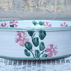 May include: White ceramic baking dish with green and pink floral design and two handles.