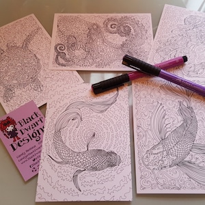 May include: Five printable colouring pages featuring intricate line art designs of a turtle, a dragon, a jellyfish, and two koi fish. The pages are printed on pink paper and are ready to be coloured with markers.