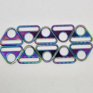 May include: Eight iridescent metal strap sliders with a rainbow finish. Each slider has a triangular shape with a circular hole and a rectangular bar. The hardware is arranged in two rows of four on a white background.