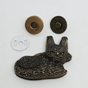 May include: A bronze-toned magnetic snap closure featuring a sculpted cat design. The set includes a decorative cat-shaped magnetic piece, a circular magnetic counterpart, and a small silver-colored metal washer with two rectangular slots.