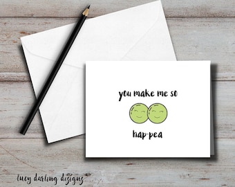 May include: A white card with black text that reads "You make me so hap-pea". The text is accompanied by a cartoon image of two green peas with smiling faces.