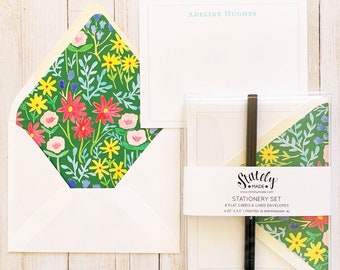 May include: A set of stationery featuring a floral design with pink, red, yellow, and blue flowers on a green background. The set includes 6 flat cards and 6 lined envelopes. The cards are 4.25 inches by 5.5 inches and are printed in Birmingham, Alabama.
