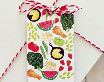 May include: A white gift tag with a colorful illustration of various foods, including watermelon, fried chicken, green beans, tomatoes, and biscuits. The tag has the words "TO:" and "FROM:" printed on it.