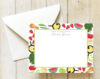 May include: A white card with a green border featuring a colorful illustration of fruits, vegetables, and kitchenware. The text "From the kitchen of Emma Grace" is printed at the top of the card.
