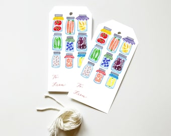 May include: Two white gift tags with a hand-drawn illustration of jars filled with various fruits and vegetables. The tags have the words "To:" and "From:" written in red ink.