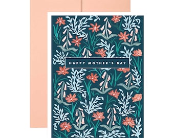 May include: A greeting card with a dark teal floral pattern and the words "HAPPY MOTHER'S DAY" in a white rectangle. The card has a peach-colored envelope. The floral design includes red, white, and green elements.