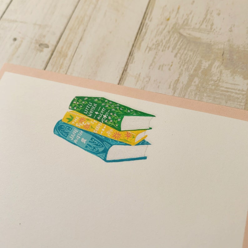 May include: A stack of three vintage paperback books with floral designs on the covers. The top book is green with the title "Little Women" by Alcott. The middle book is yellow with the title "The Secret Garden" by Burnett. The bottom book is blue with the title "Jane Eyre" by Bront&euml;.