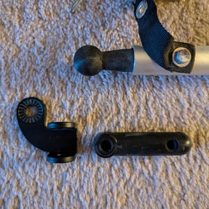 以下が含まれることがあります： 黒色の自転車用トレーラー部品のコレクション。ヒッチ、コネクティングロッド、ボールジョイントが含まれています。これらの部品は金属とプラスチックでできており、トレーラーを自転車に接続するように設計されています。