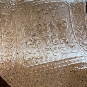 May include: A white crocheted throw blanket with the words "Live Better, Love More" in raised lettering.