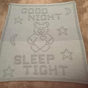 May include: A light blue crocheted blanket with the words "Good Night" and "Sleep Tight" in white. The blanket features a star and a crescent moon design.