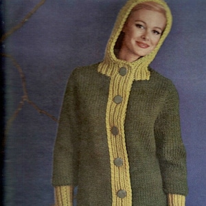 Könnte beinhalten: Ein gestrickter Kapuzenpullover mit einem gelben Streifen auf der Vorderseite und gelben Bündchen. Der Pullover hat einen Knopfverschluss und wird von einer Frau mit einem Pudel getragen.