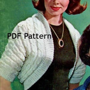 May include: White knitted cropped cardigan with a cable knit pattern. The cardigan is open in the front and has long sleeves. The text "PDF Pattern" is visible in the image.
