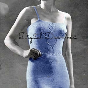 May include: A blue knitted swimsuit with a lace-like pattern. The swimsuit has a scoop neck and thin straps. The model is wearing the swimsuit and has a neutral expression.