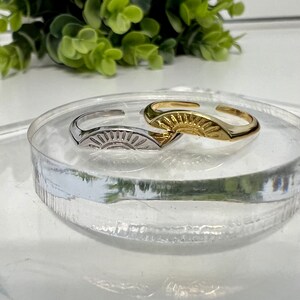 May include: Two adjustable rings with a sun design. One ring is gold and the other is silver.