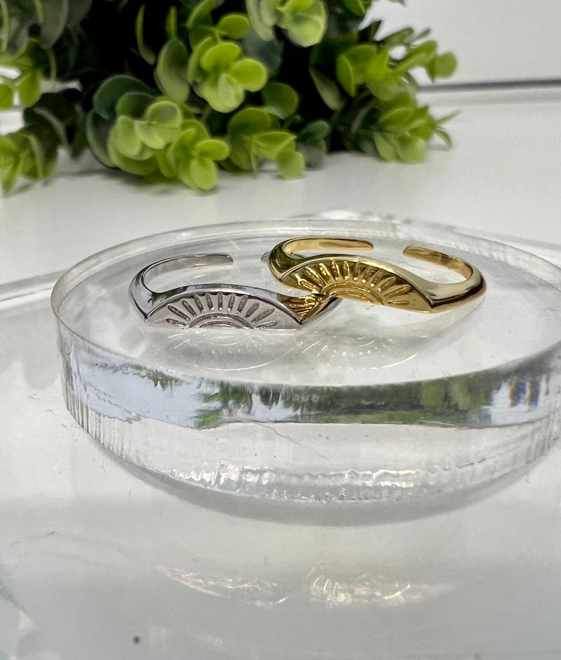 May include: Two adjustable rings with a sun design. One ring is gold and the other is silver.