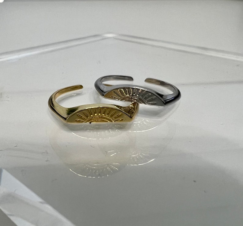 May include: Two adjustable rings with a sun design. One ring is gold and the other is silver.