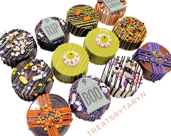 Könnte beinhalten: Eine Sammlung von Halloween-Schokoladen-Leckereien. Die Leckereien sind mit bunten Streuseln, Schokoladenguss und Fondant-Akzenten verziert, darunter Grabsteine mit den Worten "RIP" und "BOO". Einige Leckereien haben ein Augendesign.