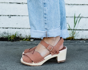 May include: Brown leather open-toe heeled sandals with a criss-cross strap design and a wooden platform sole.