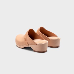 Malmö-style clogs designed by Sandgrens in classic Ecru Beige  leather. Featuring a smooth, slip-on design with a supportive strap for stability. The sturdy wooden sole and hand-stapled construction ensure durability and all-day comfort, making them a stylish and functional footwear choice.